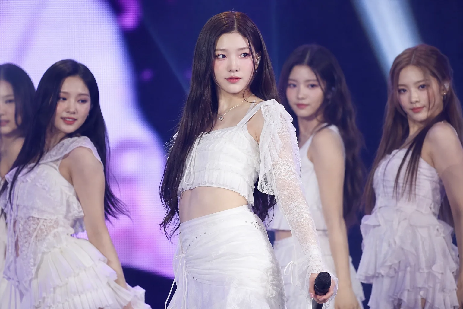 K-pop performers on a modern festival stage with handheld microphones