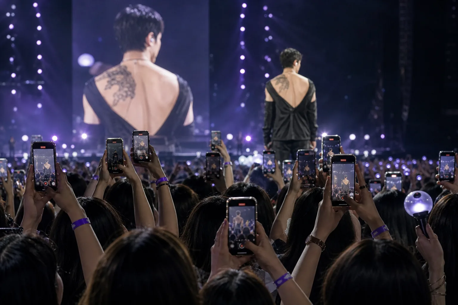 Concert audience watching a K-pop performance as fans discuss possible BTS tattoo reveal