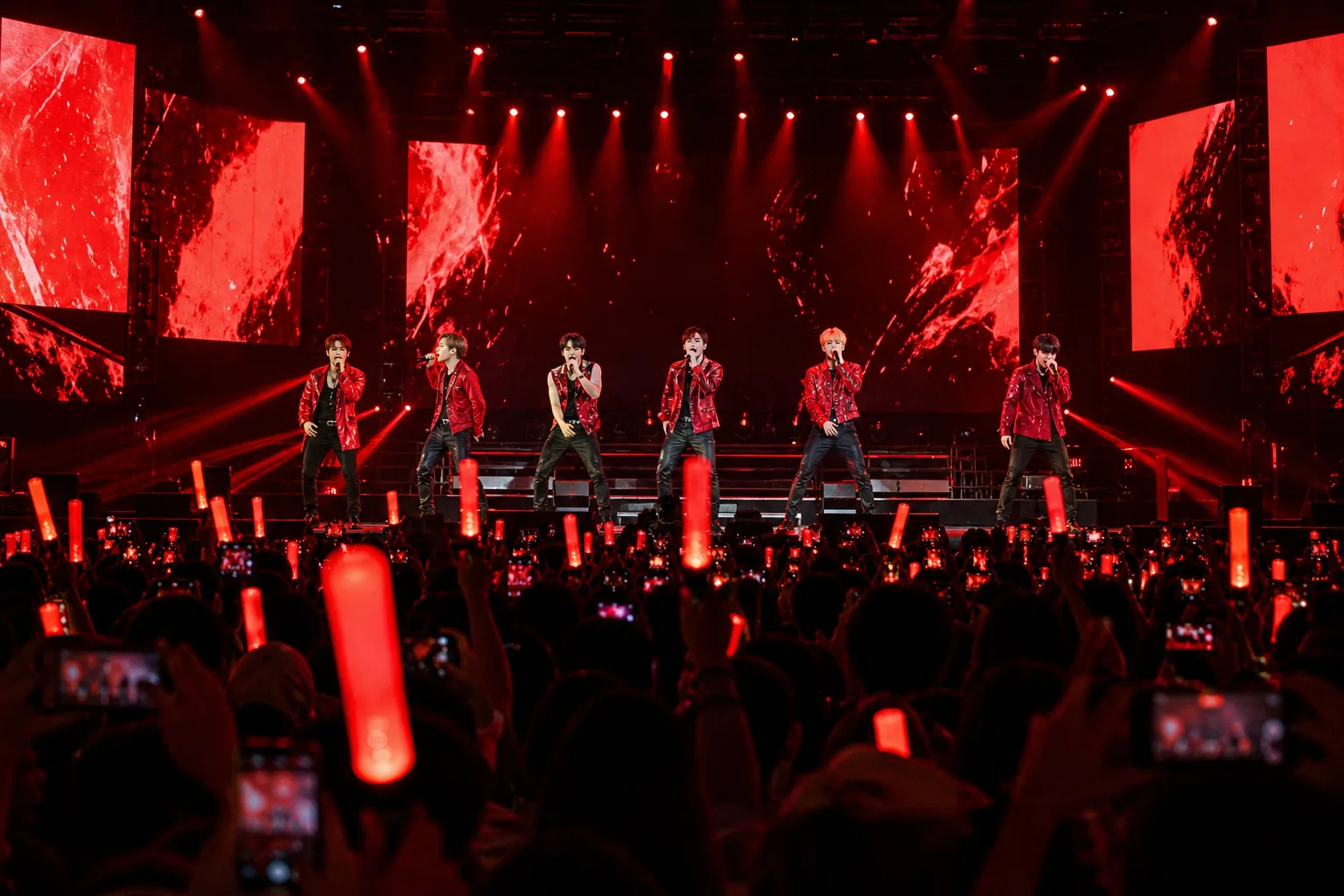 K-pop group concert with fans holding red lightsticks in a large Manila venue