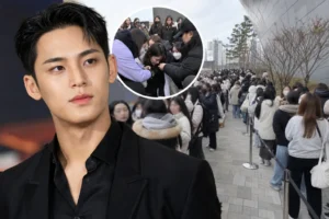 Fans waiting in a long queue for a K-pop event in a city shopping district
