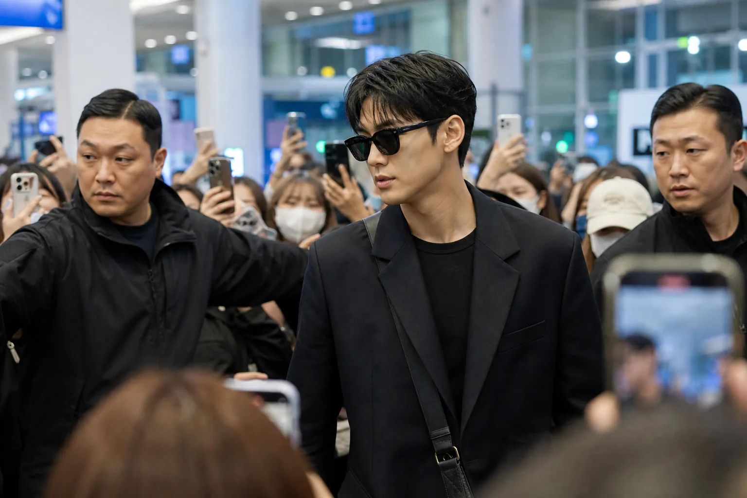 Fans keeping distance at an airport barrier during a celebrity arrival