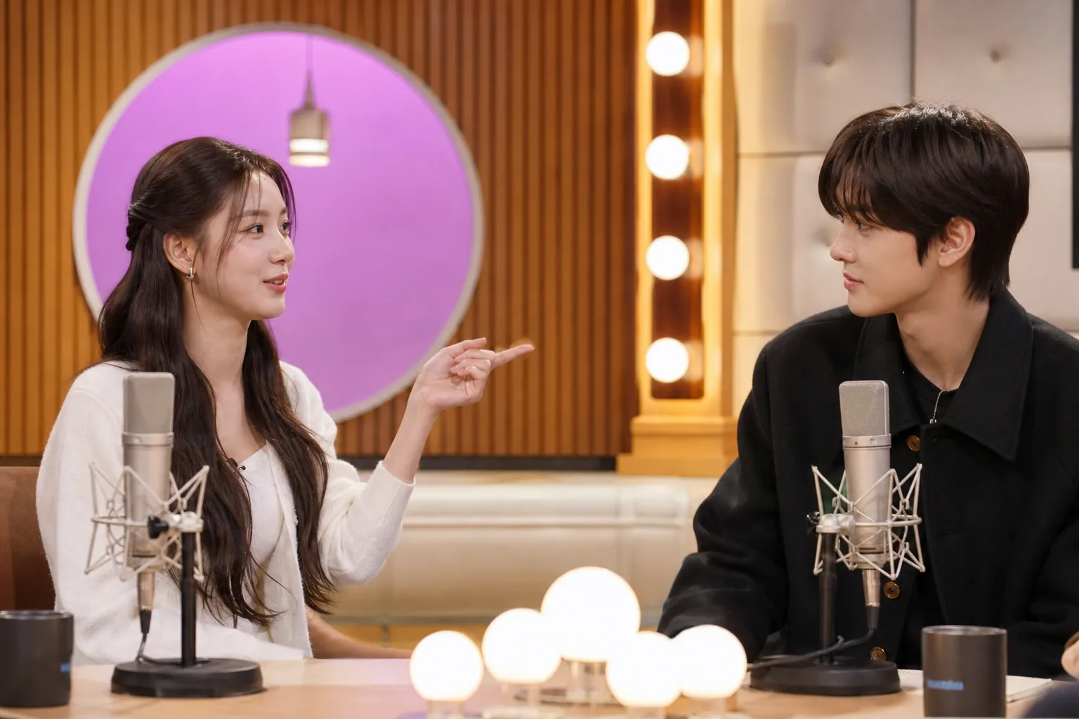 K-pop idols in a bright studio setting during a variety show conversation