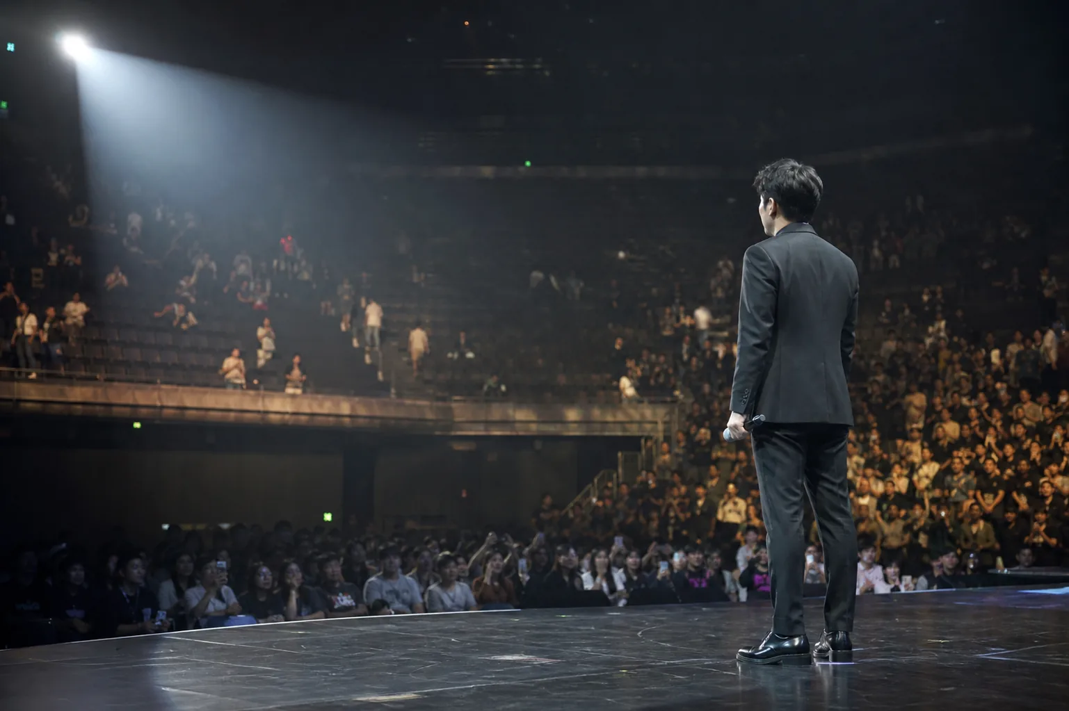 Empty concert seats and stage lights symbolizing audience pressure in Korean entertainment