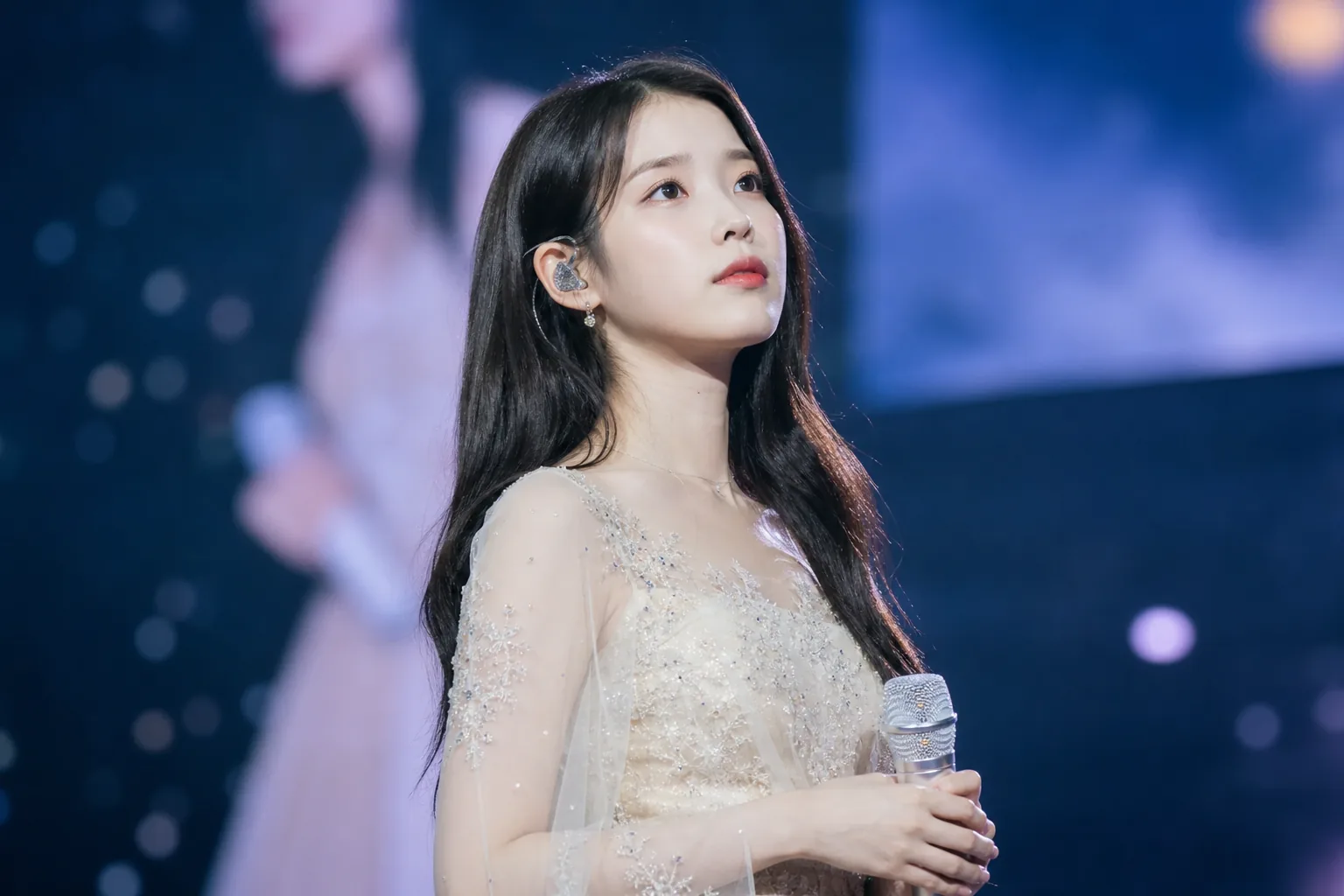Concert microphone and in-ear monitor symbolizing IU pausing live performances for health reasons