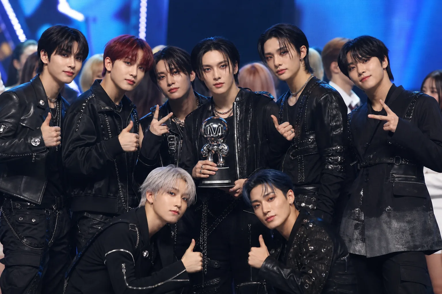 K-pop group celebrating a music show trophy on stage