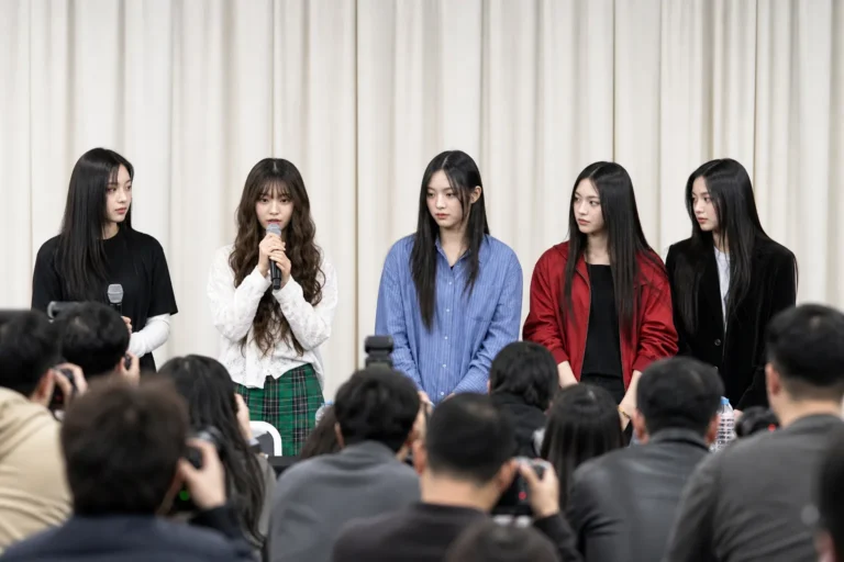 Editorial image of a Korean entertainment press conference representing NewJeans comeback scrutiny