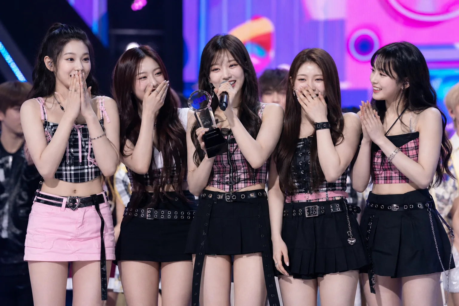 K-pop group celebrating a first music show trophy after a live performance