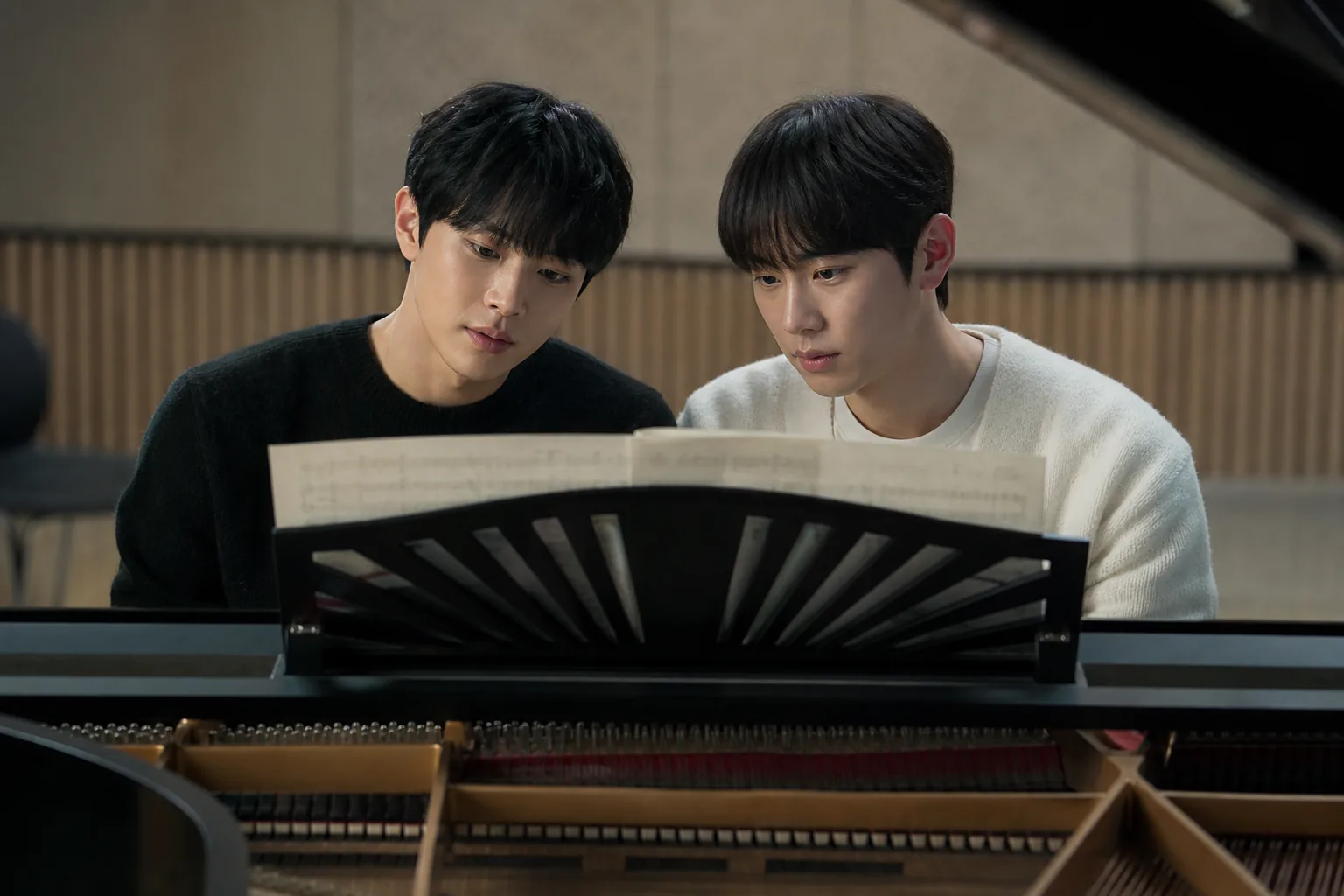 Two pianists rehearsing a four hands duet on one piano in a Korean drama setting