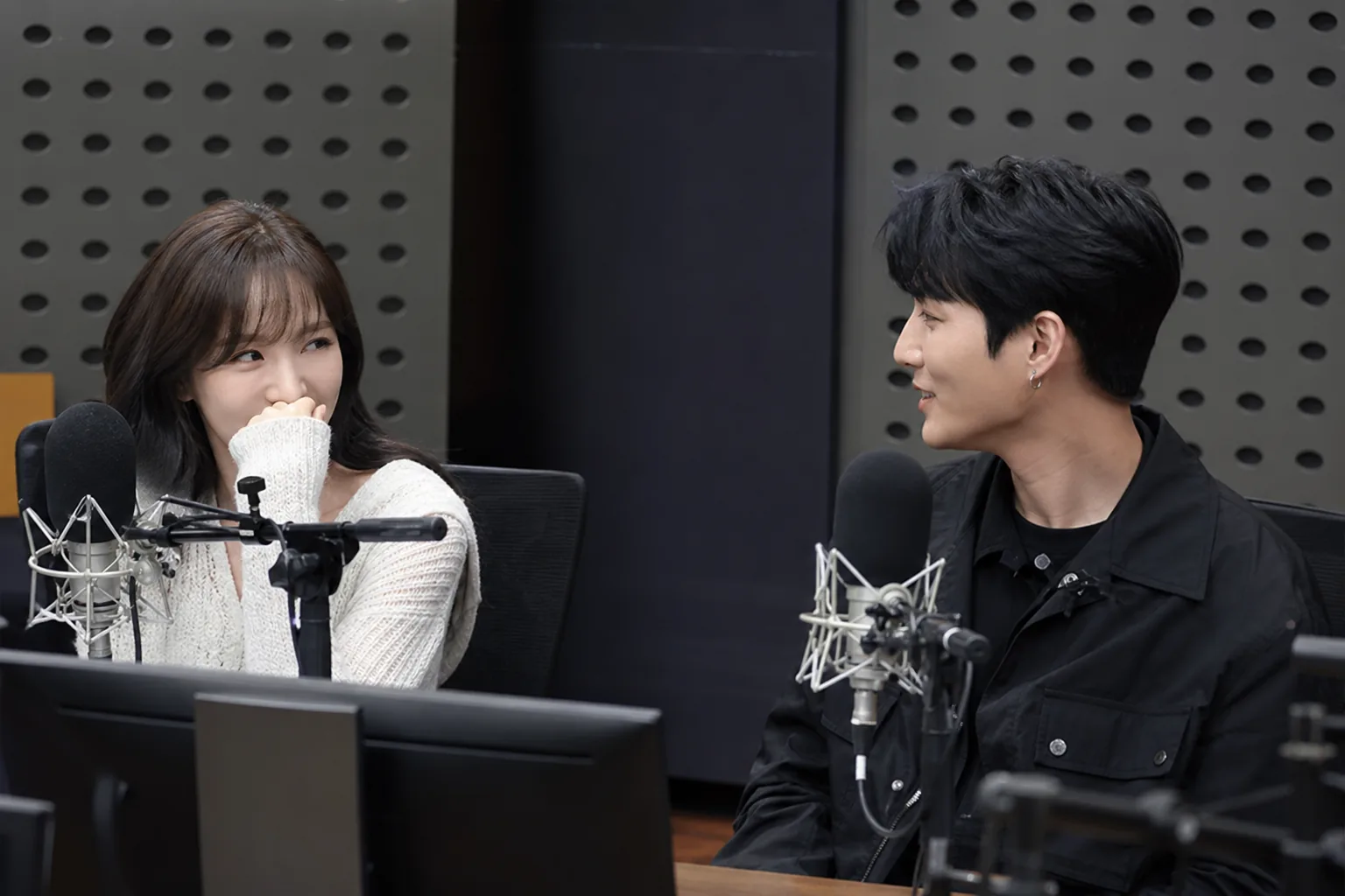 Radio broadcast studio scene showing two K-pop artists in conversation