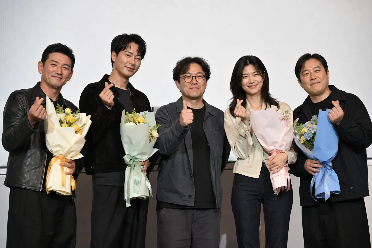 Film cast and director gathered in a warm studio setting after a successful release