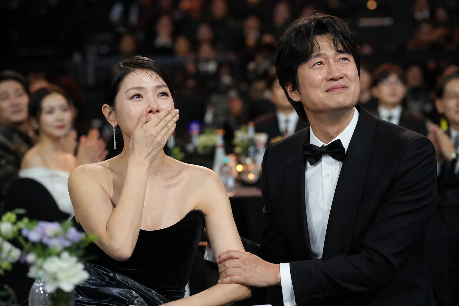 Korean actress receiving an award on a bright ceremony stage
