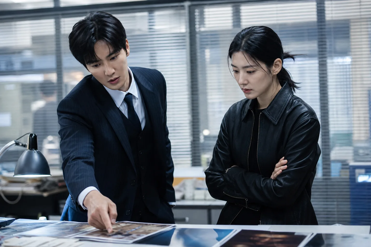 Two Korean detectives reviewing evidence in a modern investigation office