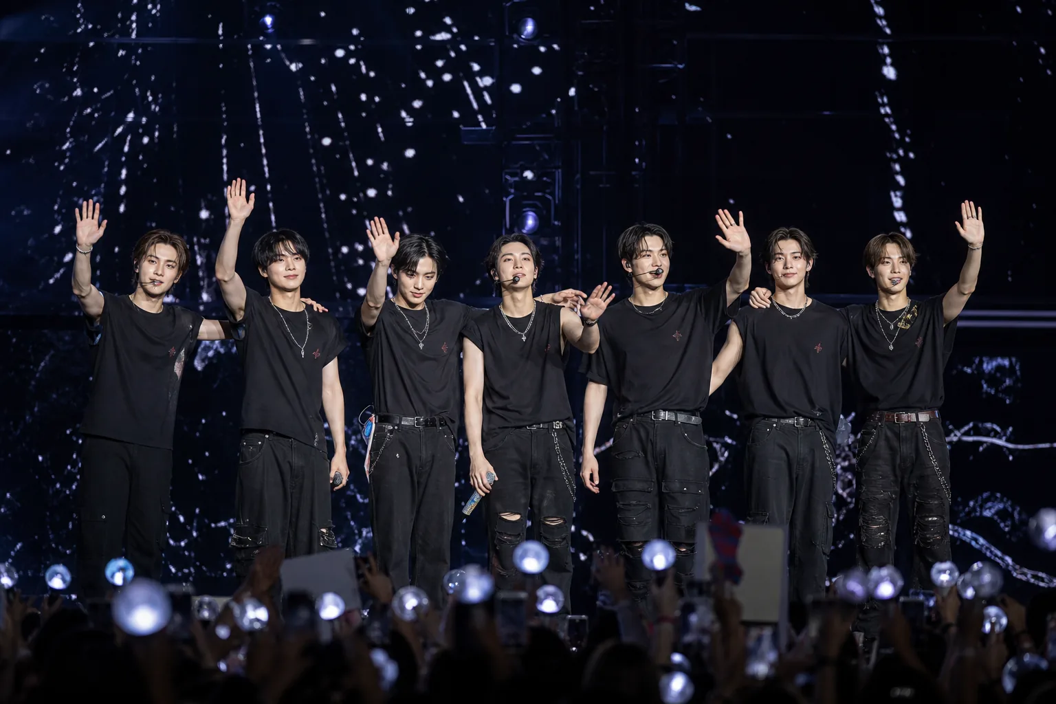 K-pop performers on a dramatic concert stage with blue and red lighting