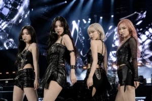 Four K-pop performers on a large outdoor festival stage at night