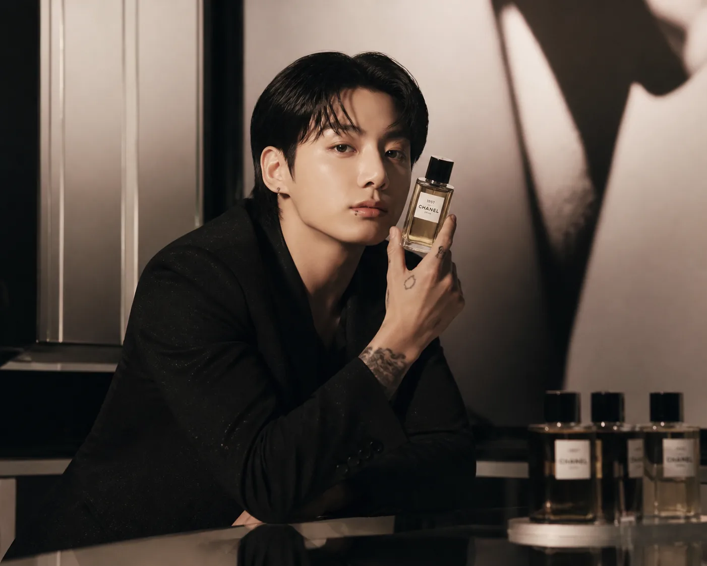 Close editorial composition of a clear fragrance bottle in dramatic soft light