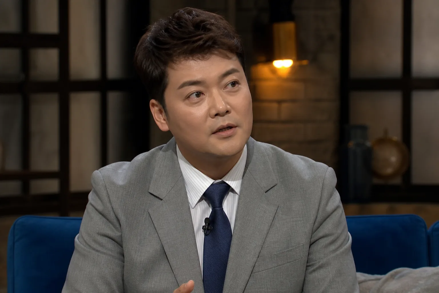 Korean television host seated in a thoughtful studio discussion