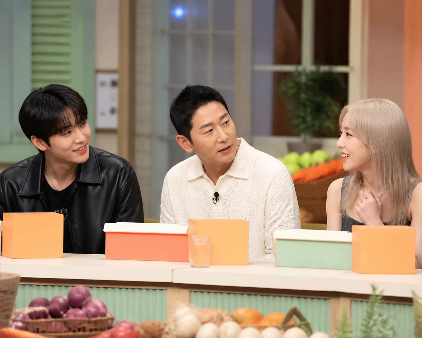 Variety show guests and hosts sharing a lighthearted studio conversation